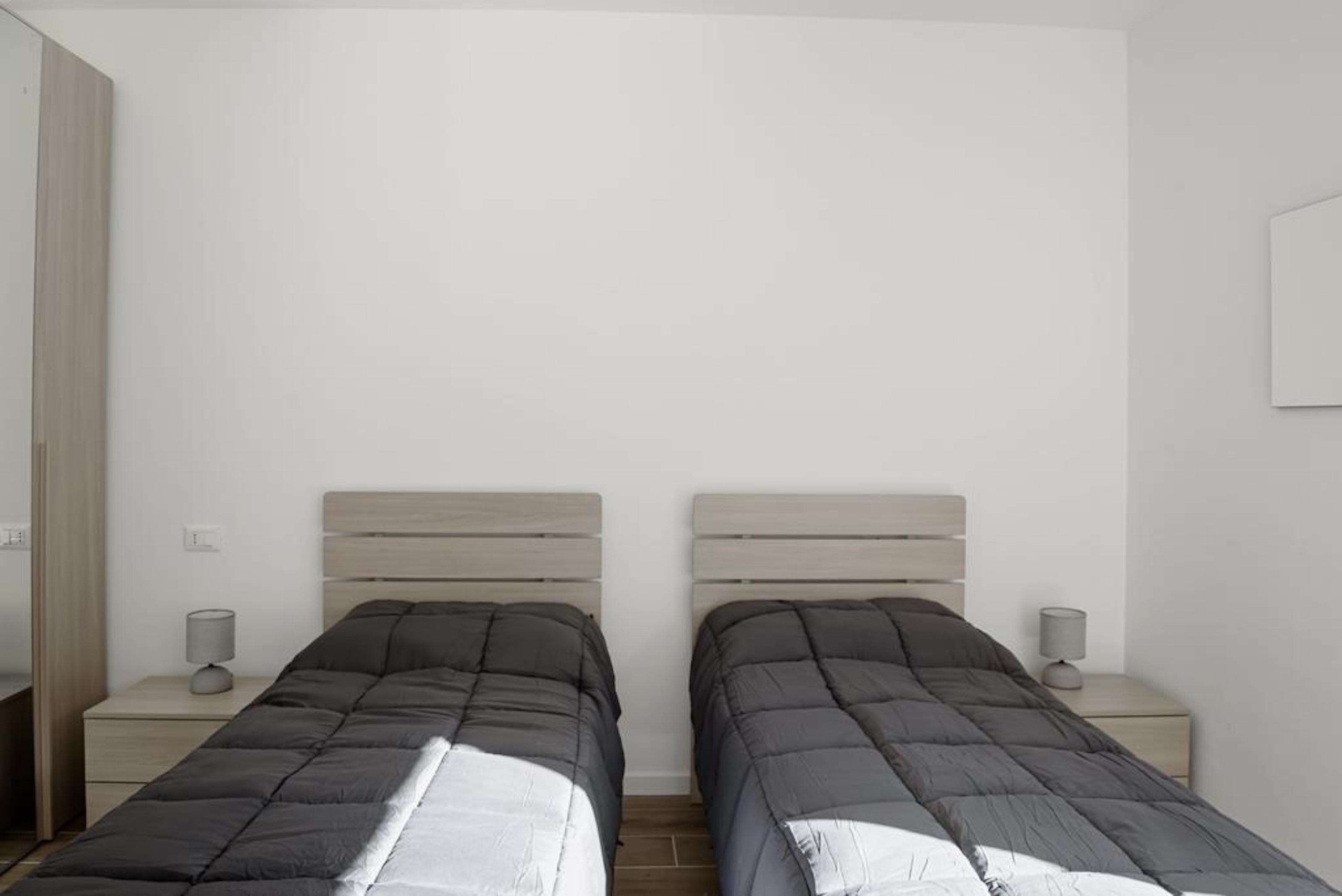 Une chambre à coucher avec deux lits, chacun doté d’une tête de lit en bois, d’une table de chevet et d’une lampe.