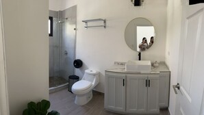 Un baño con inodoro, lavamanos, espejo y ducha.