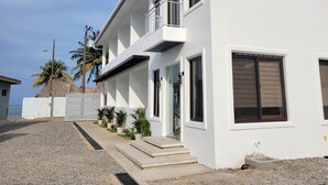 Una casa moderna de dos pisos con balcón, puerta principal y un pequeño porche.