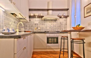 A kitchen with white cabinets, a stove, a sink, and a wooden floor.