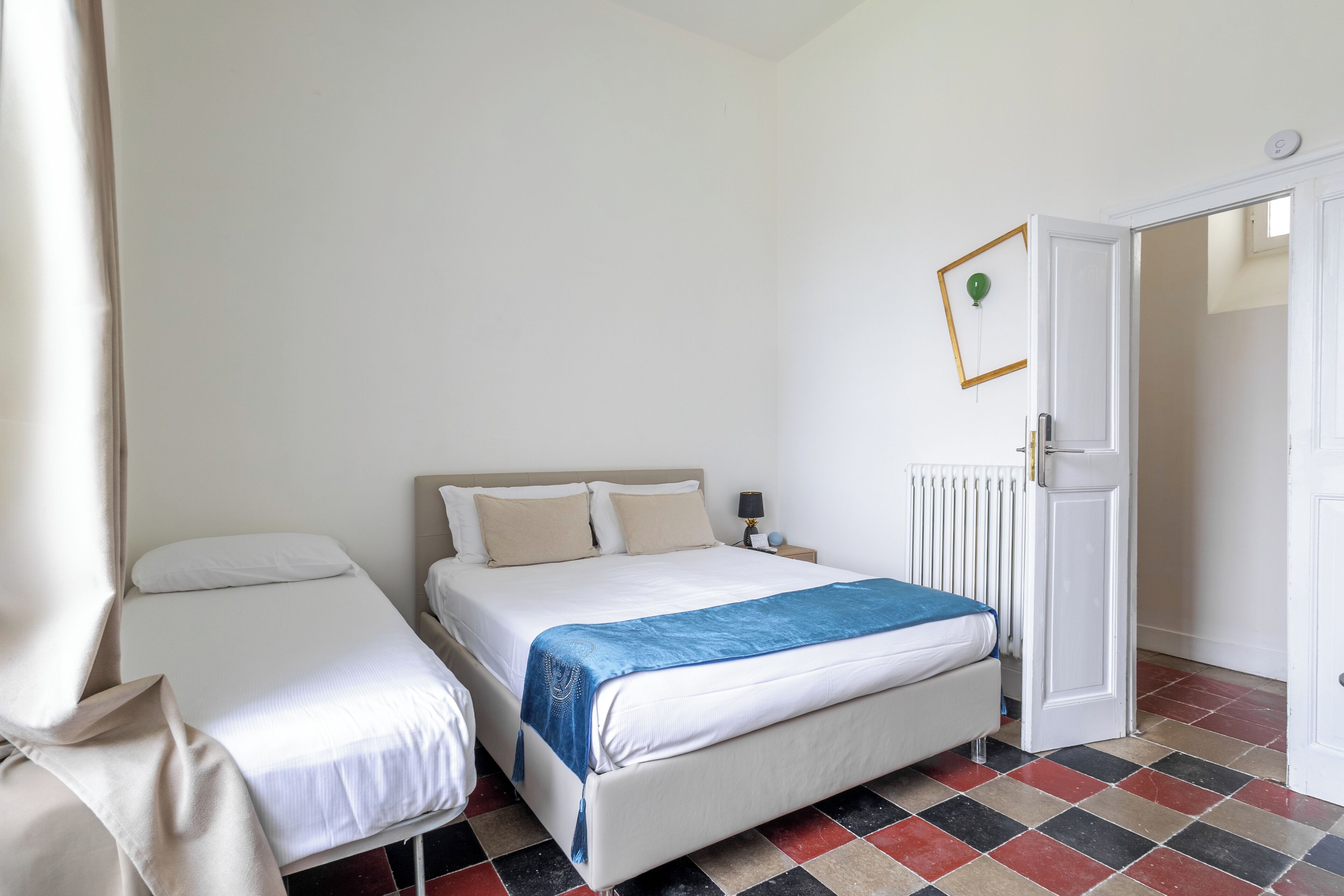 A bedroom with a bed, a bedside table, a lamp, and a radiator.