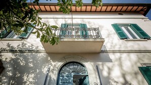 A building facade with a balcony, a door with a decorative arch, and a window with shutters. - Palazzo Dasso (Viterbo)