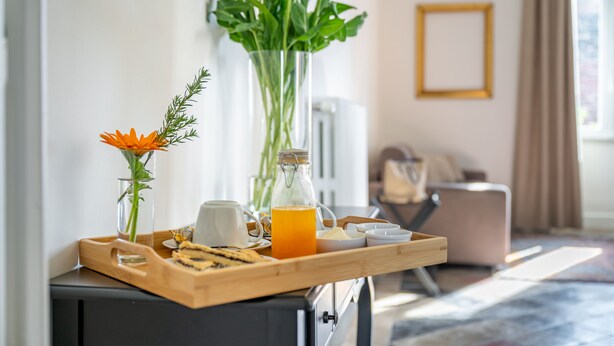 A breakfast tray with orange juice, a white mug, and a glass of orange juice on a wooden tray. - Palazzo Dasso (Viterbo)