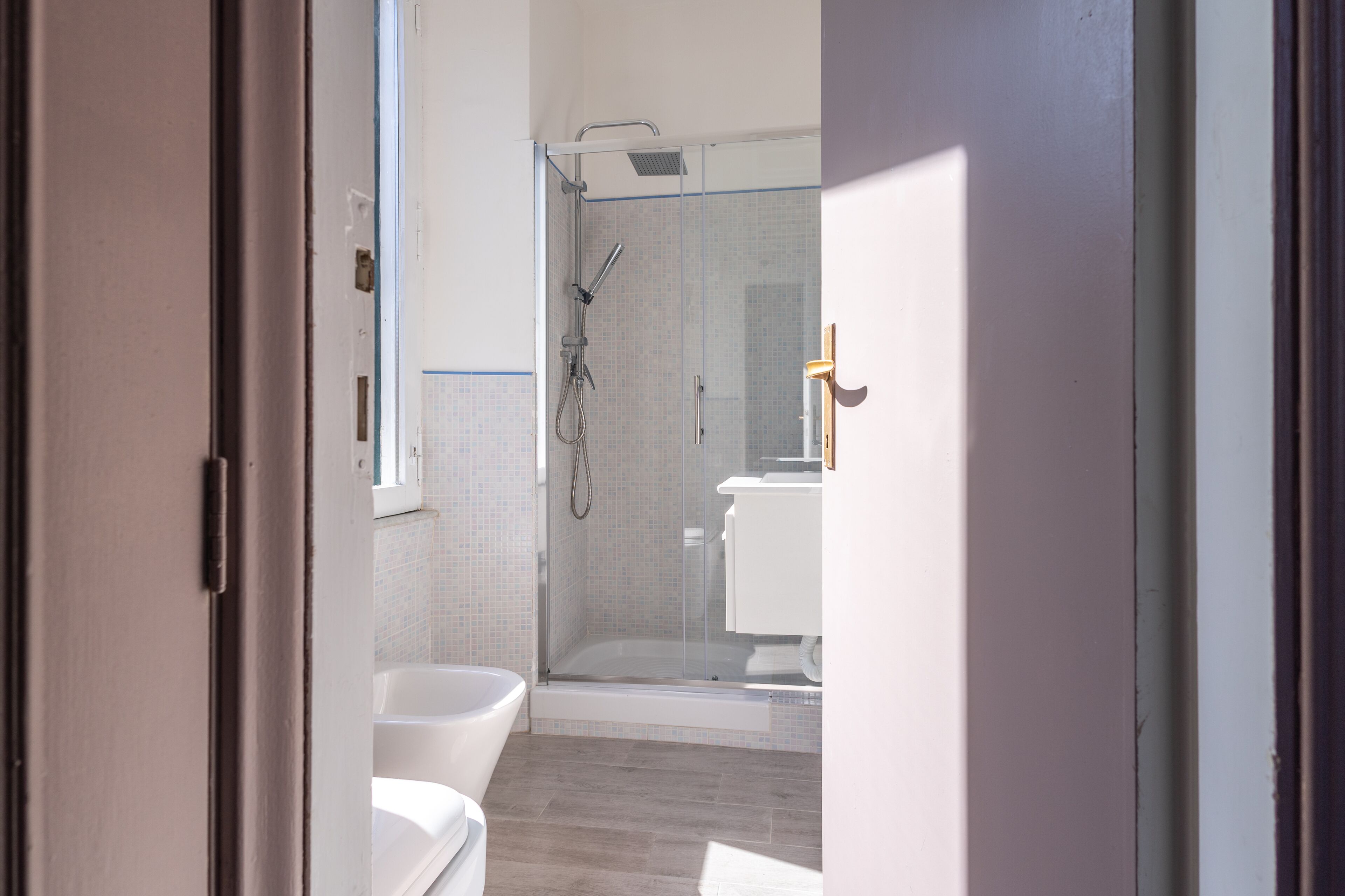 A modern bathroom with a glass-enclosed shower, a white bathtub, and a toilet.