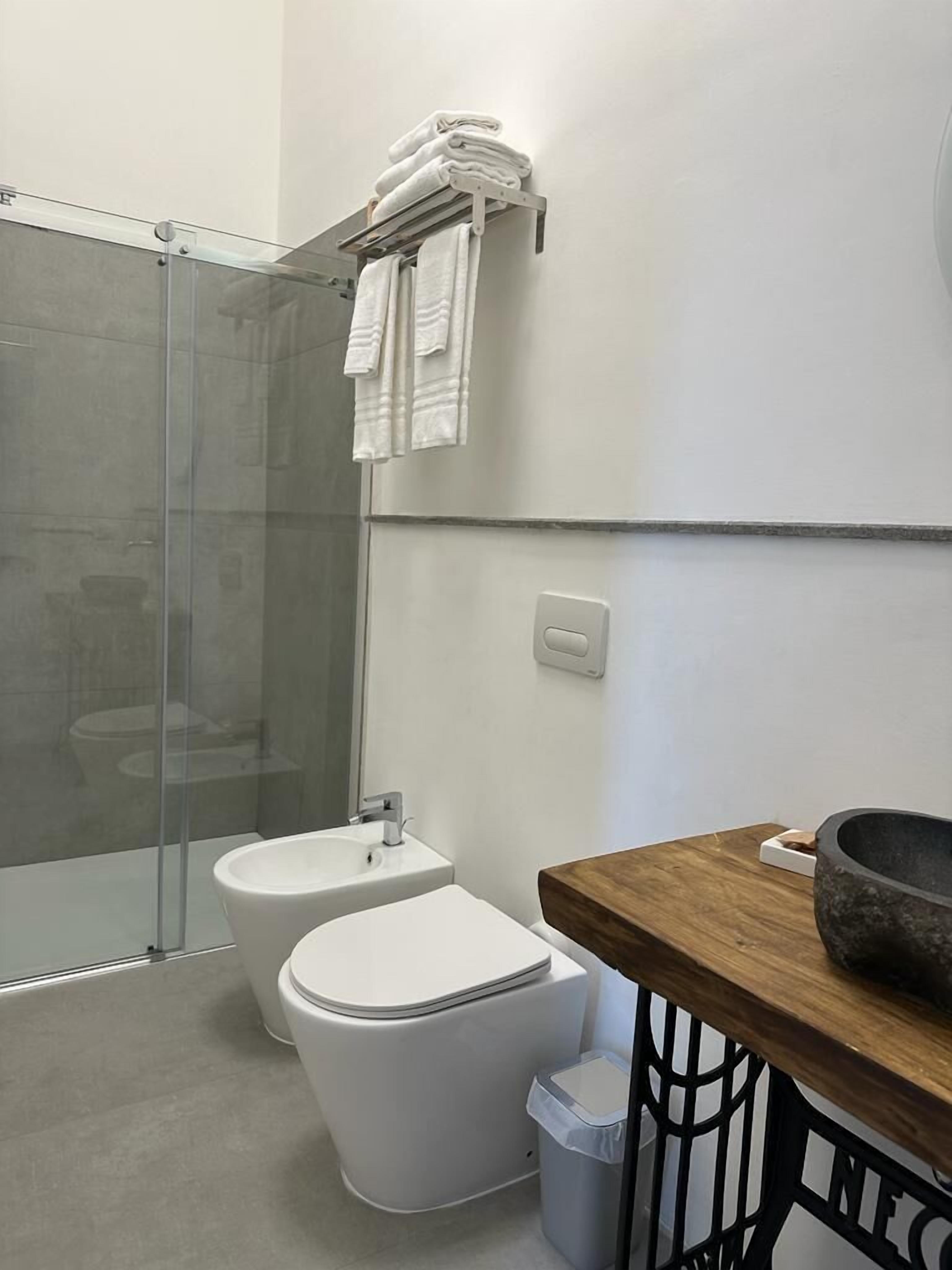 Um banheiro moderno com box de vidro, vaso sanitário e pia.