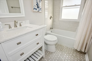 A bathroom with a white sink, two faucets, a toilet, and a bathtub.