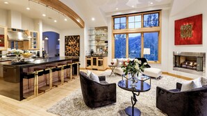 Eine moderne Küche mit Bar, Kamin und großen Fenstern mit Blick auf die Berge.
