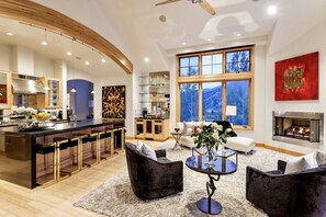 Een moderne keuken met een bar, een open haard en grote ramen met uitzicht op de bergen.