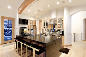 Een moderne keuken met een groot eiland, roestvrijstalen apparatuur en houten details.