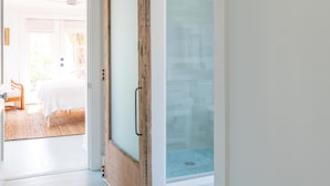 A hallway with a wooden door leading to a glass door, a white ceiling, and a view of an outdoor area with a table and chairs. - Palmetto Bungalow - Quaint, original Fairhope cottage close to town. (Fairhope)