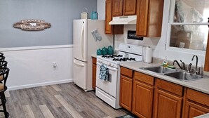Una cocina con armarios de madera, un refrigerador blanco, una estufa y un fregadero.