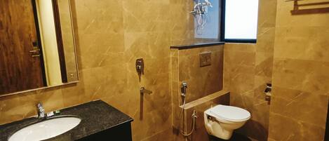 A bathroom with a marble floor, a sink, a toilet, a shower, and a hand dryer.