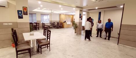 A spacious hotel lobby with multiple seating areas, a reception desk, and a clear exit sign.