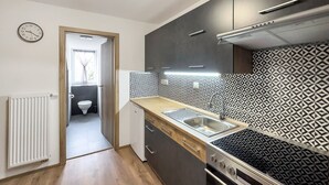 A compact kitchen with a modern stove, a sink, and a window.