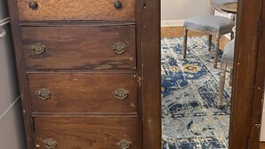A wooden dresser with a mirror, three drawers, and a small mirror above the top drawer.