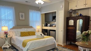 A bedroom with a bed, bedside lamps, a bedside table with a vase, a dresser, a mirror, and a rug.