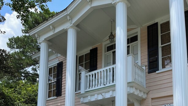 A two-story house with a balcony, columns, and a number '301' sign.