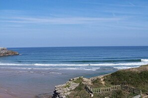 A coastal view with a wooden walkway leading to a rocky outcrop.