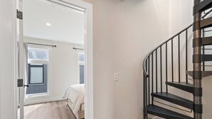 A staircase with a metal railing leading to a bedroom with a bed and a window. - BRAND NEW downtown TC rooftop condo skyline views (Traverse City)