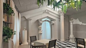Un comedor con una mesa, sillas y un arco decorativo.