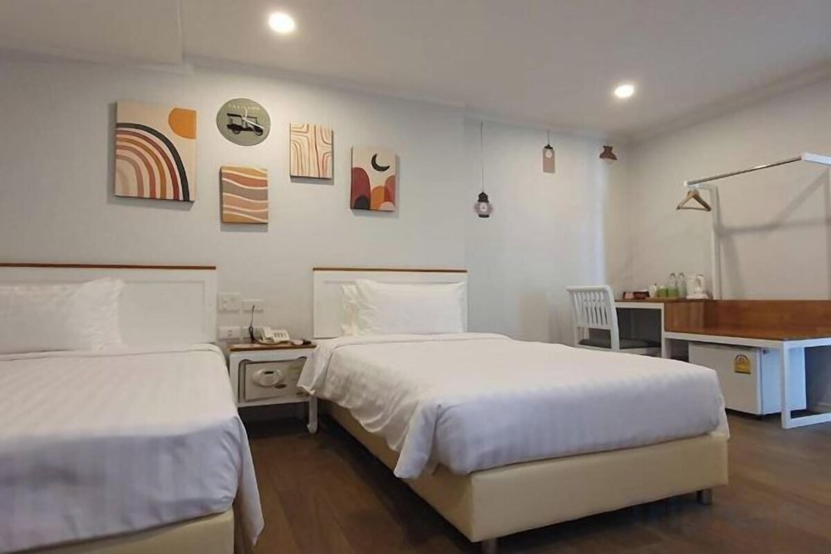 Quarto de hotel com duas camas, uma escrivaninha e uma cadeira.