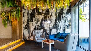 Un interior moderno con pared de mármol, zona de estar y plantas colgantes.
