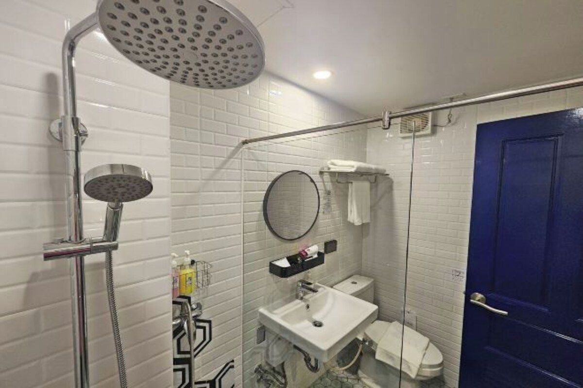 A bathroom with a shower, toilet, sink, and a blue door.