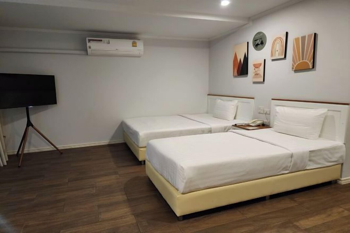 A hotel room with two beds, a flat-screen TV, and artwork on the wall.