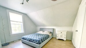 A bedroom with a bed, a nightstand, a wardrobe, a window, and a ceiling fan. - Harmonious Cottage by the river (Washago)