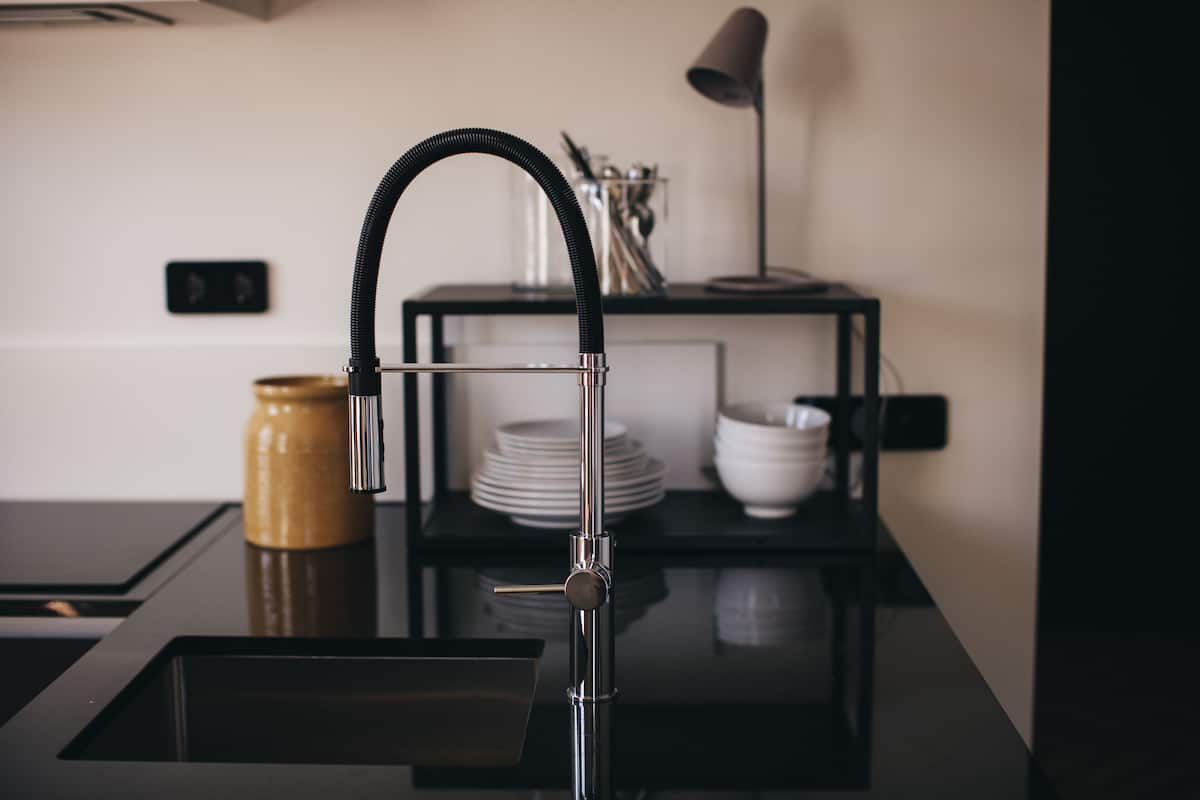Una cocina moderna con encimera negra elegante, un lavamanos de acero inoxidable y un grifo negro.
