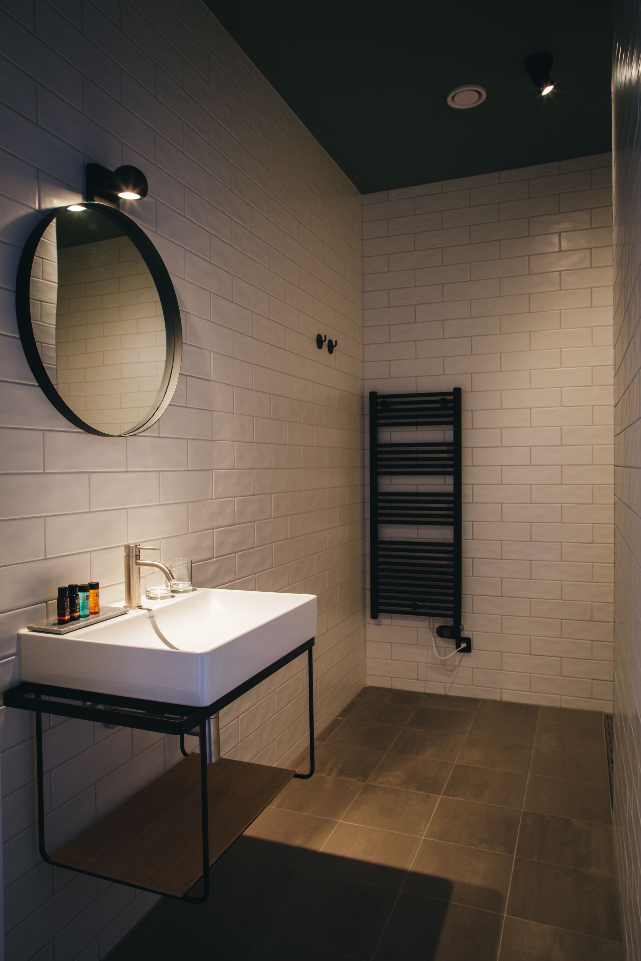 Un baño moderno con un lavamanos blanco, toallero negro y un espejo con iluminación integrada.