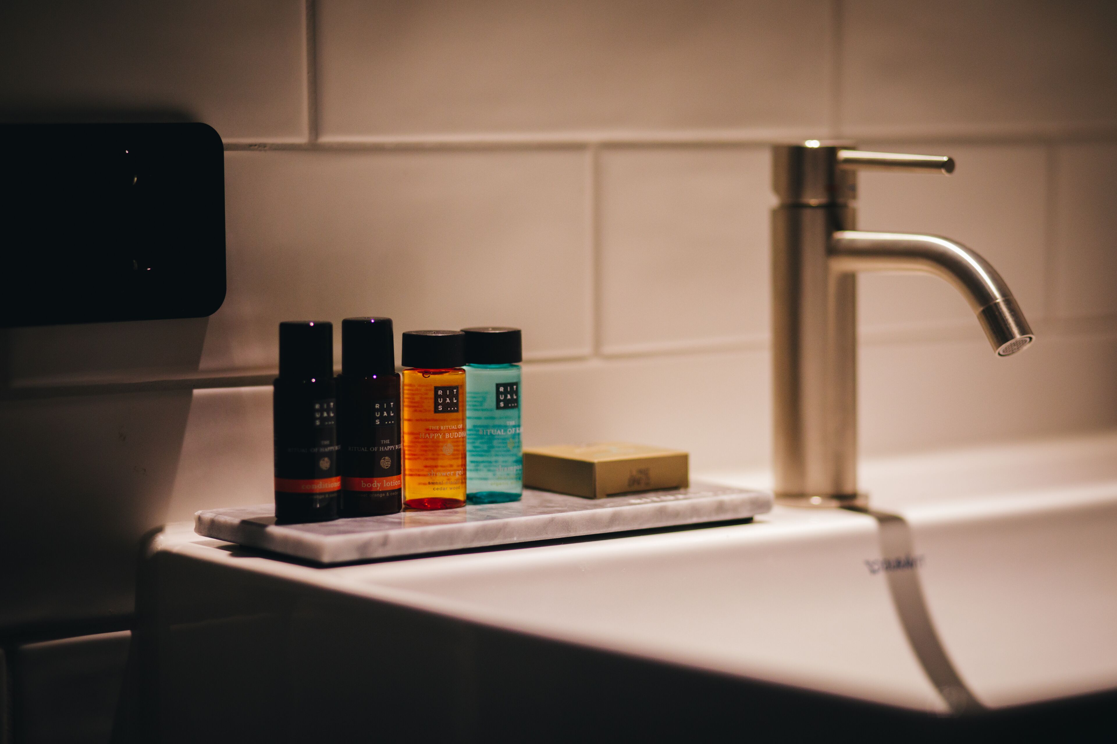 A bathroom sink with a faucet, a soap bar, and three bottles of liquid soap.
