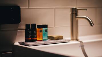 A bathroom sink with a faucet, a soap bar, and three bottles of liquid soap.