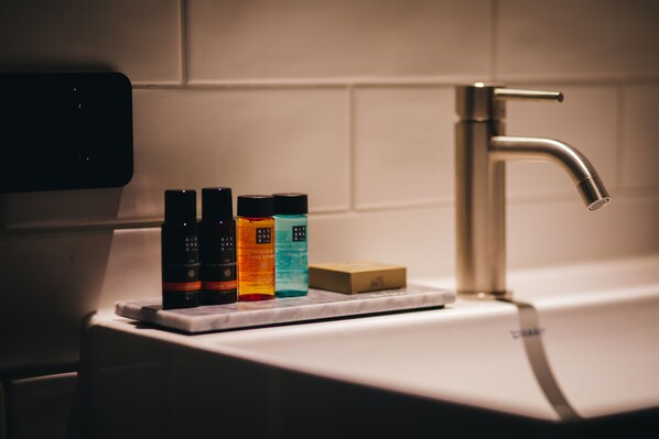 A bathroom sink with a faucet, a soap bar, and three bottles of liquid soap. - Dudok Studio's Arnhem-Oosterbeek (Oosterbeek)