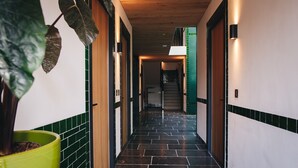 Un pasillo con techo de madera, paredes enlosadas y una escalera que sube a un nivel superior.