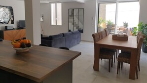 A modern living room with a dining area, a sofa, a TV, and a large window.