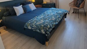 A bedroom with a large bed, wooden floor, and a ceiling light fixture.