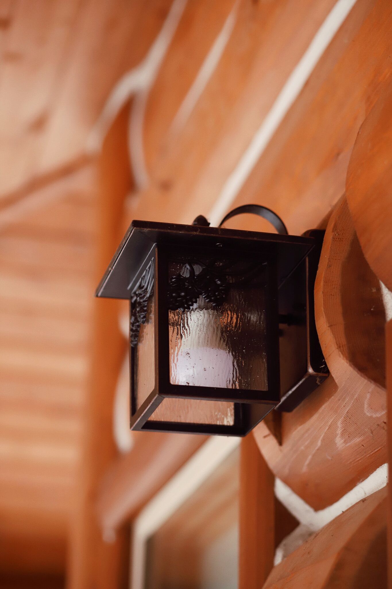 A close-up of a black lantern attached to a wooden structure.