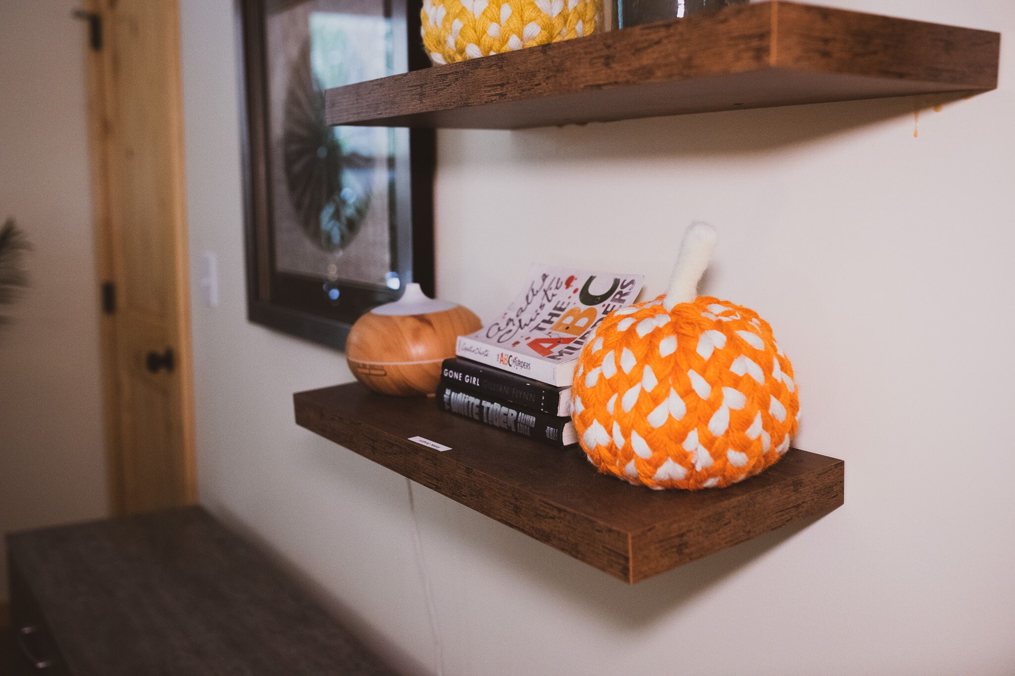 A wooden shelf with a pumpkin and books.