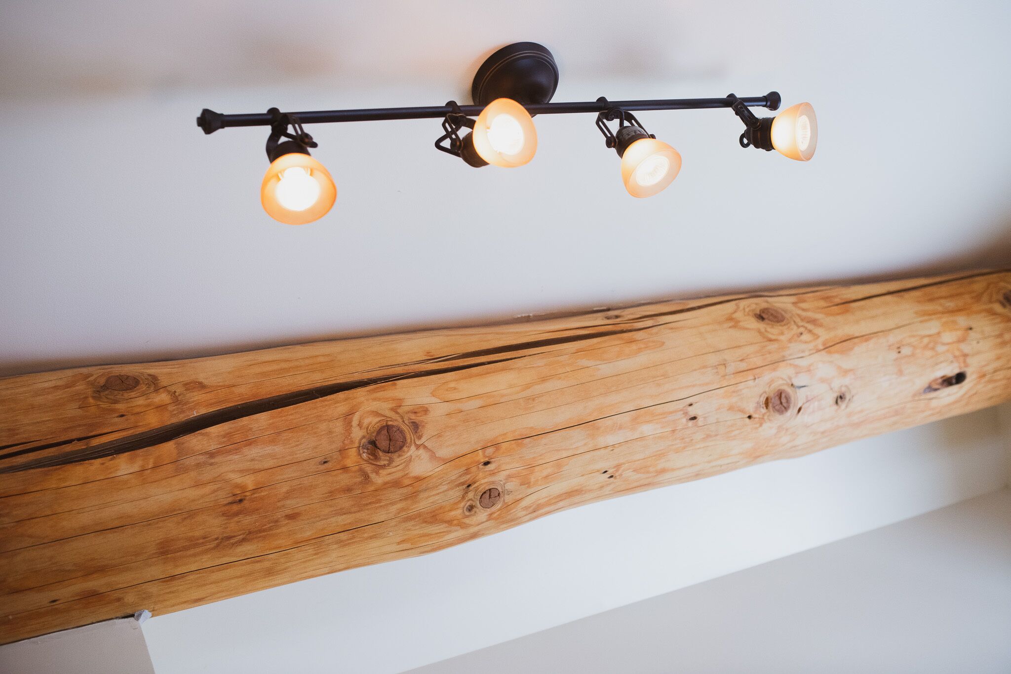 A ceiling with a wooden beam and three hanging lights.