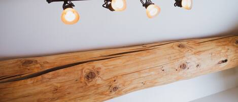 A ceiling with a wooden beam and three hanging lights.