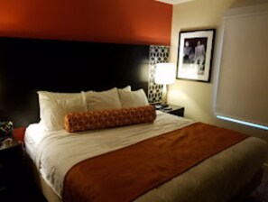 Cozy retreat with a neatly made bed, a nightstand, and a framed picture on the wall.
