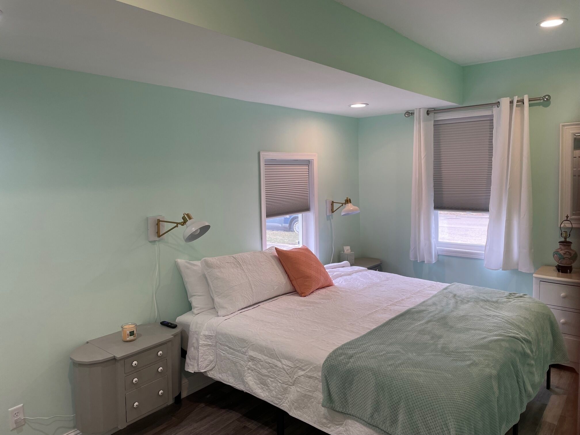 A bedroom with a bed, bedside tables, lamps, and a window with curtains.