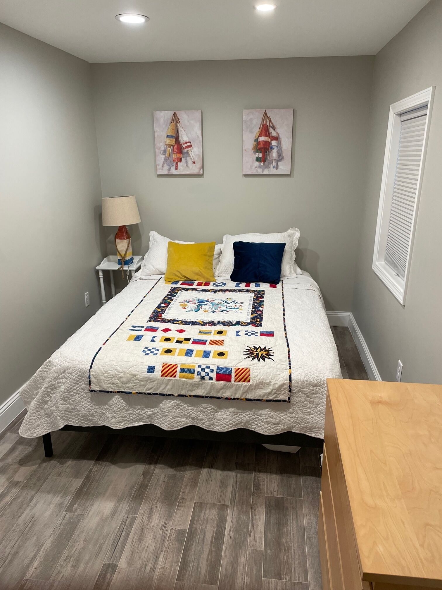 A bedroom with a bed, a nightstand, a lamp, and artwork on the wall.