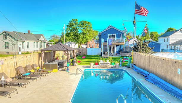 Ein Garten mit Swimmingpool, Liegestühlen und einer überdachten Terrasse.