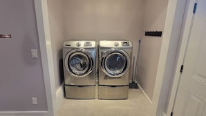 Une buanderie équipée de deux machines à laver à chargement frontal et d’un panneau « DÉFENSE DE FUMER » sur la porte.