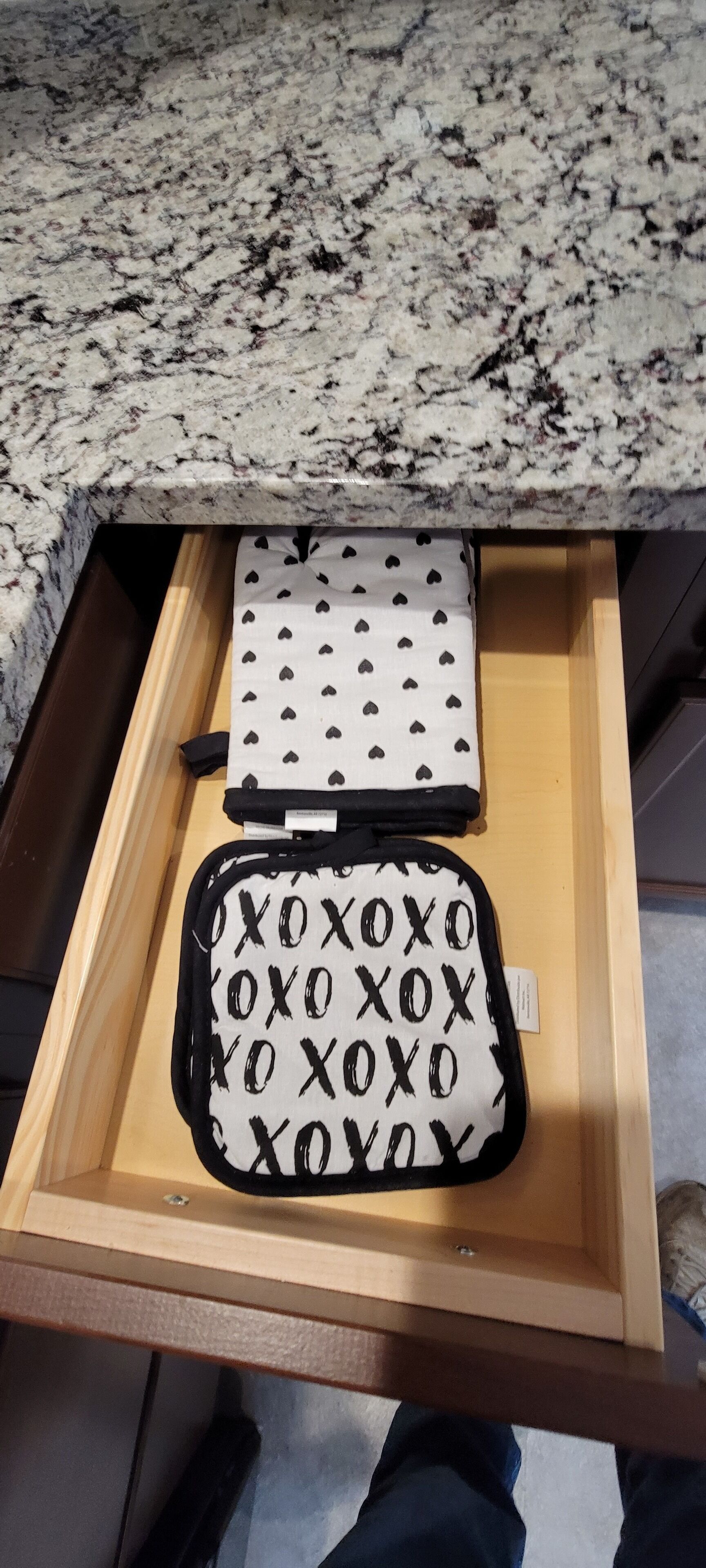 A drawer with two storage bags, one with a heart pattern and another with 'XOXO' text, on a granite countertop.