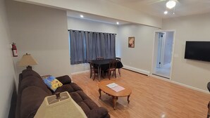 Un salon comprenant un canapé, une table basse, un téléviseur et un coin repas avec une table et des chaises.