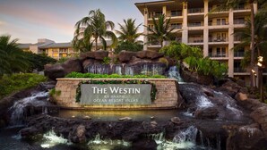 Le Westin Kona Resort Villas, avec sa cascade, ses palmiers et son panneau indicateur.