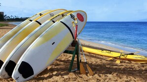 Une plage avec des planches de surf et un kayak.
